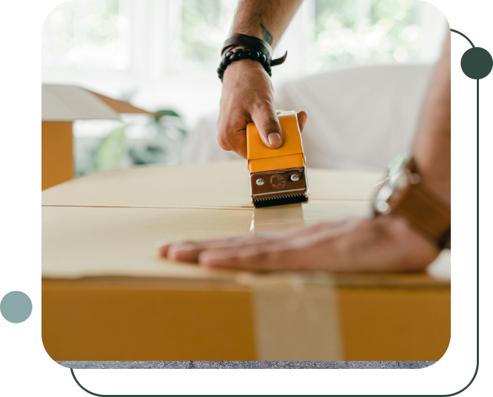 A person sealing a cardboard box with packing tape using a tape dispenser.