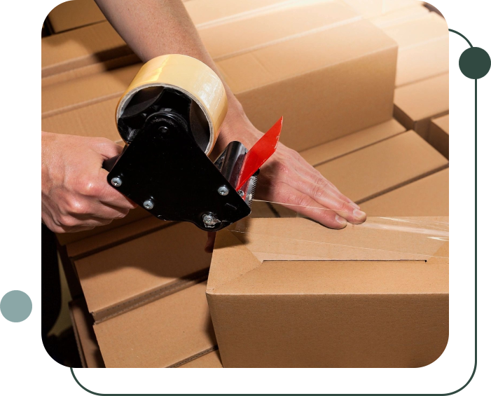 A person sealing a cardboard box with clear packing tape using a tape dispenser.